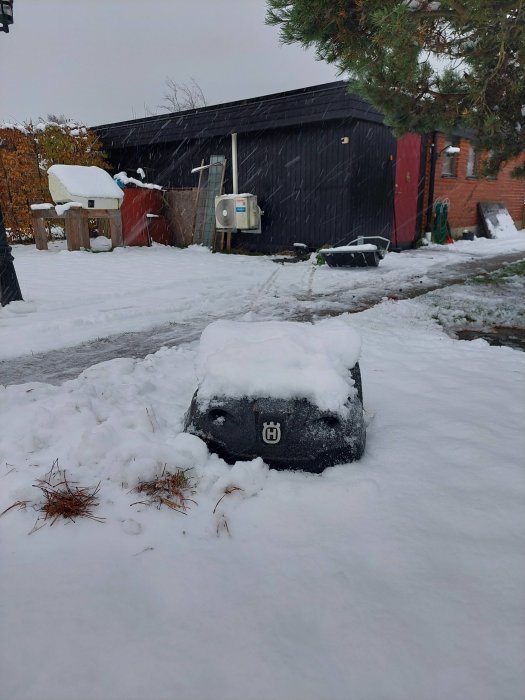 Snötäckt utomhusmiljö med föremål och byggnader; molnig himmel syns.