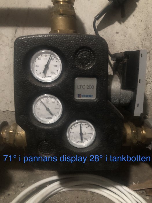 Värmeregulator med mätare på betongvägg, ESBE LTC 200, kablar, röranslutningar, text på svenska.