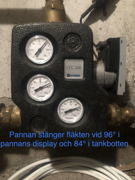 Termometer, esbe LTC 200 enhet, kablage, text om panninställning, betongvägg bakgrund.