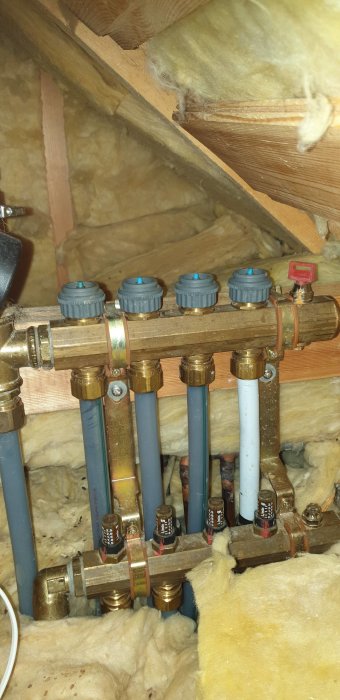 VVS-installation med rör och ventiler, isolering syns, husets inre struktur, underhålls- eller installationsarbete kan förestå.