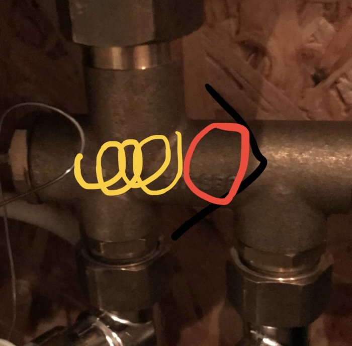 Rörkopplingar, ventiler, träbakgrund, markerade cirklar, svart pil, gul spirallinje. Inomhusinstallation, fokus på rördetaljer.