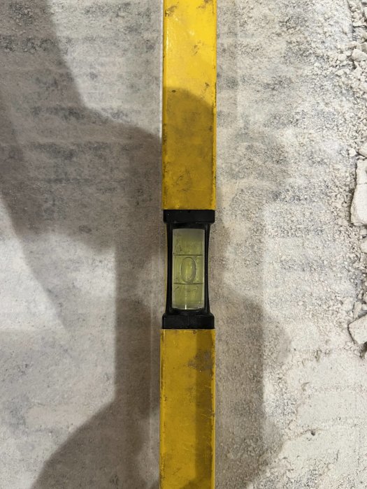 Vattenpass centrerat på gult och slitet verktyg mot betongyta.