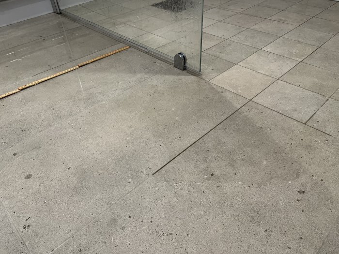 Golvet med plattor, en spegelvägg, och en metallstång vid spegelns fot.