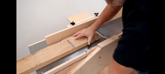 En person förbereder ett trästycke för kapning eller bearbetning på ett bänkformat verktyg.