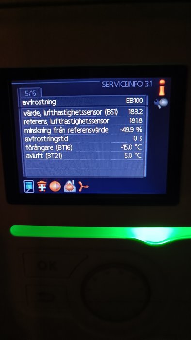 Digital display med teknisk information om avfrostning och sensorvärden, knappar nedanför, grönt ljus till vänster.