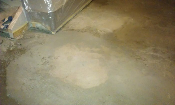 Et mislykket hallgulv med ujevnt flytspackel, synlige sandkorn, områder med glasfiber på overflaten, og uherdede, myke flekker etter to dager.