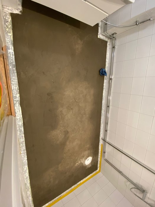 Renovering av badrum pågår, betonggolv gjutet, väggar och installationsrör synliga, kakel halvvägs upp.