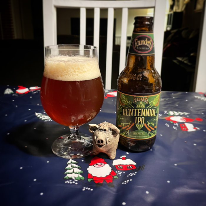 Öl i glas, IPA flaska, liten grisfigur, julduk med snögubbar och granar.