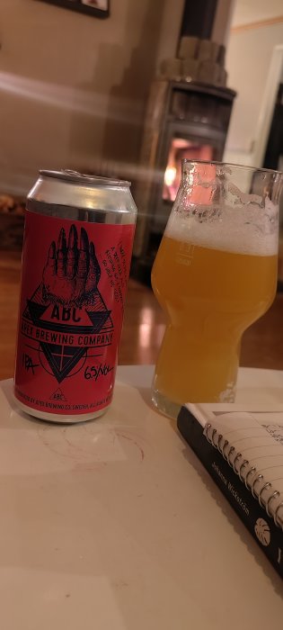 Ölburk och glas framför brasa, anteckningsbok på bordet. Inomhus, avkopplande stämning.