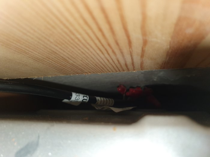 Sladdar och föremål i ett trångt, dammigt utrymme mellan träpaneler och mörk bakgrund.