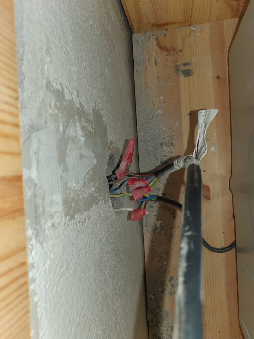 Öppen, oavslutad elektrisk dosa med kabelskarvar, byggarbetsplats, säkerhetsrisk, oorganiserat, väggmontage, kablar.