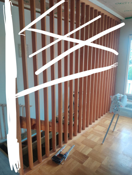 Inredning under konstruktion, träpelare, verktyg på golvet, delvis oskarp bild med vita sträck och fläckar.