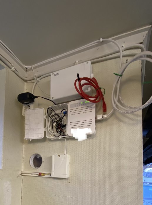 Oorganiserad elinstallation med kablar, enheter, och antenn på vägg och tak.