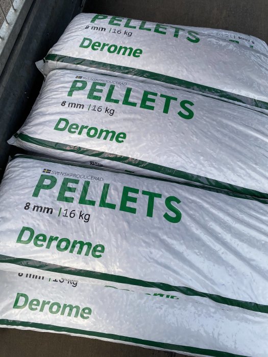 Flera säckar med pellets märkta "Derome", "8 mm" och "16 kg", staplade ovanpå varandra.