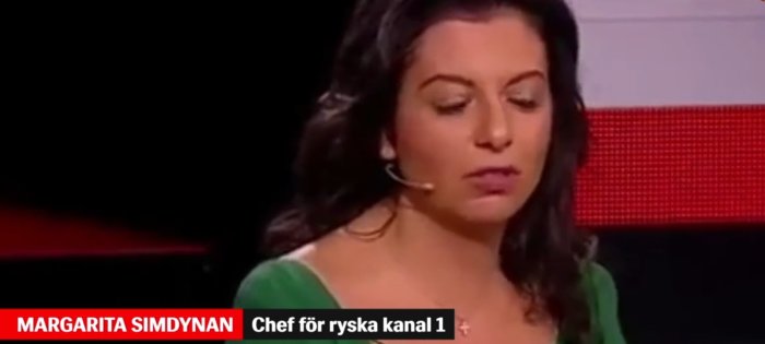 Kvinna i grönt, titelrad angiver position på rysk TV-kanal, ser allvarlig ut.