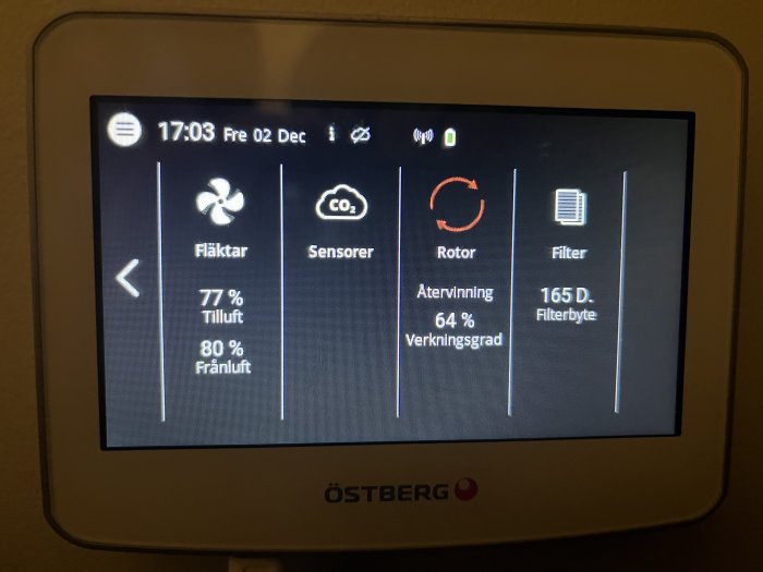 Digital display visar ventilationssystemstatus: fläktar, sensorer, värmelagring, filterbyte, på svenska, med tidsangivelse.