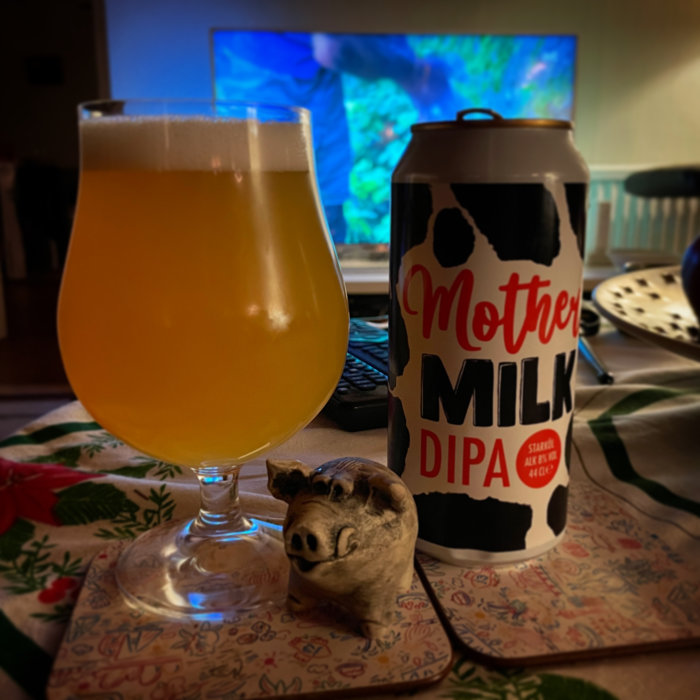 Öl i glas bredvid en burk, prydnadsgris framför, TV i bakgrunden. Myshörna med dryck och dekoration.