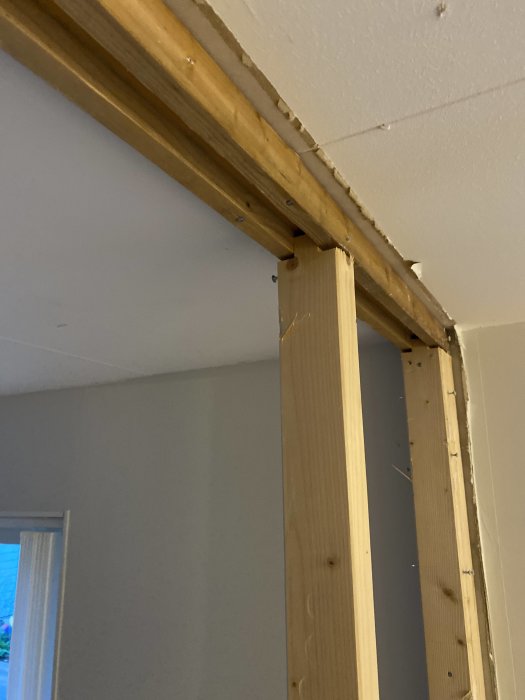 Renovering pågår, träreglar syns där vägg och tak möts, ofärdiga ytor, byggnadsställning eller ombyggnation.