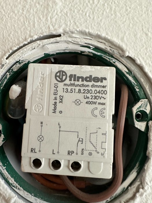 Finder multifunktionsdimmer installerad i vägg, elektriskt kopplingsschema synlig, väggfärg runtomkring, 230V märkning.