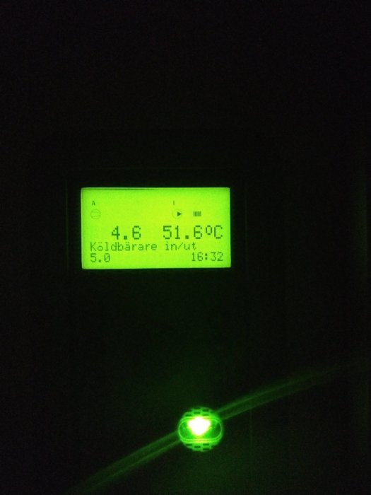 Digital display i mörker visar temperatur 51.6°C, med grön bakgrundsbelysning och reflekterande grön knapp nedanför.