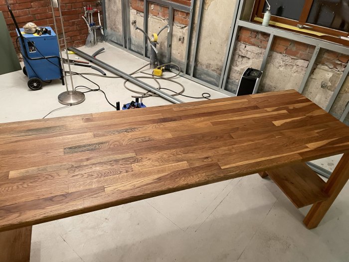 Träbord i förgrunden, verktyg och byggmaterial i ett under konstruktion rum bakgrunden.