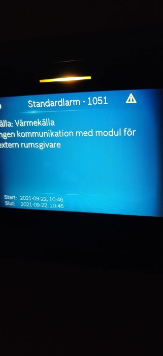 Ett alarmlarmfel på en skärm indikerar saknad kommunikation med en extern rumsgivare för uppvärmningssystem.