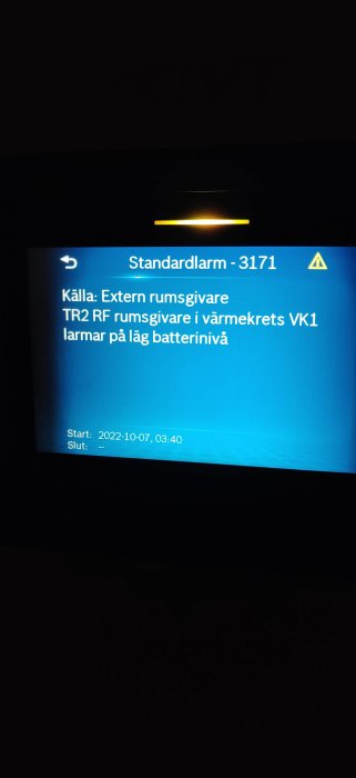 Ett larmmeddelande på skärm meddelar låg batterinivå på en extern rumsgivare.