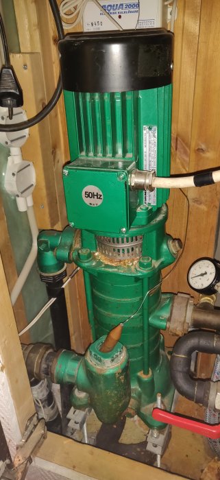 Grundfos husvattenverk, rostig, tryckmätare, rör, elkabel, installationsmiljö, teknisk utrustning, pumpsystem, elektrisk kalkborttagare.