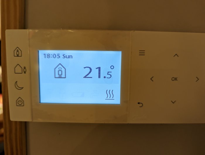 Digital termostat visar tid, dag, inomhustemperatur på 21,5 grader Celsius med touch-knappar.