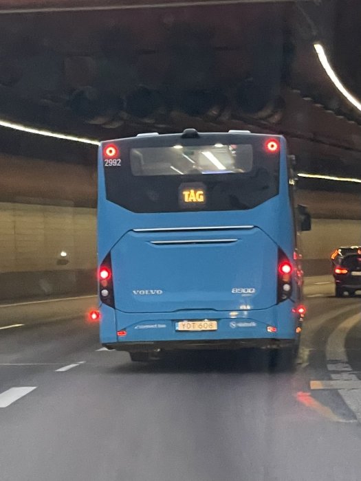 En blå buss av märket Volvo i en tunnel med texten "TÅG" på skylten.