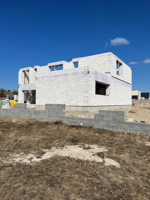 Nybyggt hus i betongblock, ofärdigt, blå himmel, byggplats, dagtid.