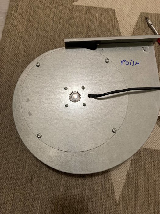 Omvänd vy av en robotdammsugare på en matta, med handskrivet "Pojk" på den.