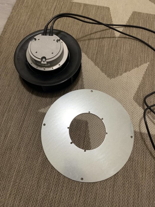 Rund taklampa demonterad på ett golv, med kabel och monteringsplatta synliga.