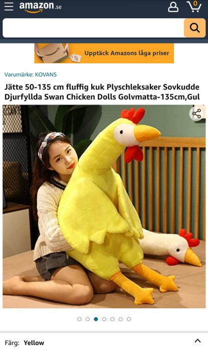 Kvinna håller ett stort gult kycklingplyschleksak i ett rum.