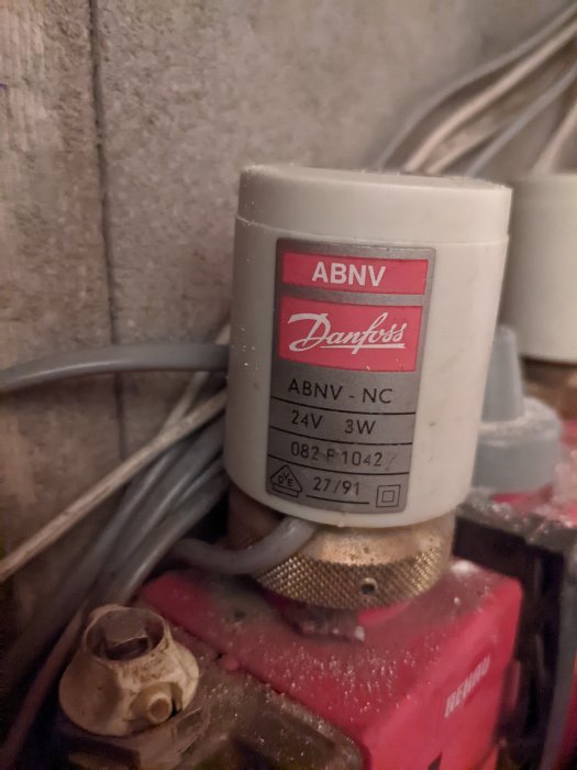 Danfoss magnetventil med etikett, kablar, och anslutningar i teknisk installation, dammig och använd.