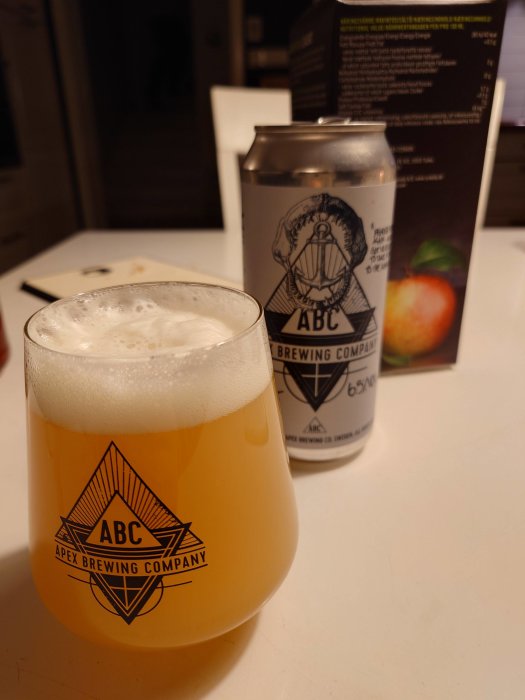 Ölglas på bord, skum, ölburk, Apex Brewing logo, inomhus, bordsytan, oskarp bakgrund.