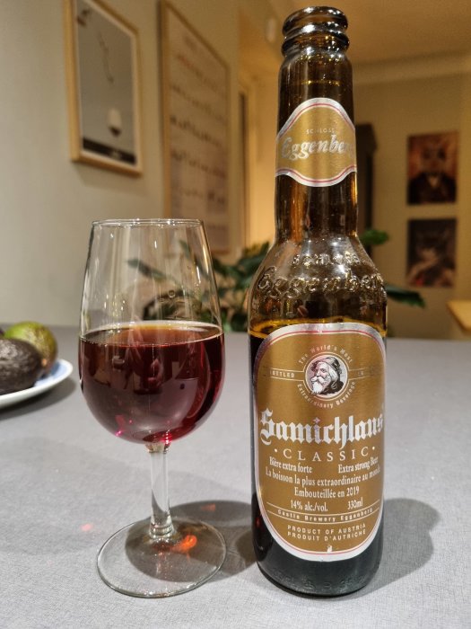 Ett glas mörk öl nära en öppnad ölflaska på ett köksbord.