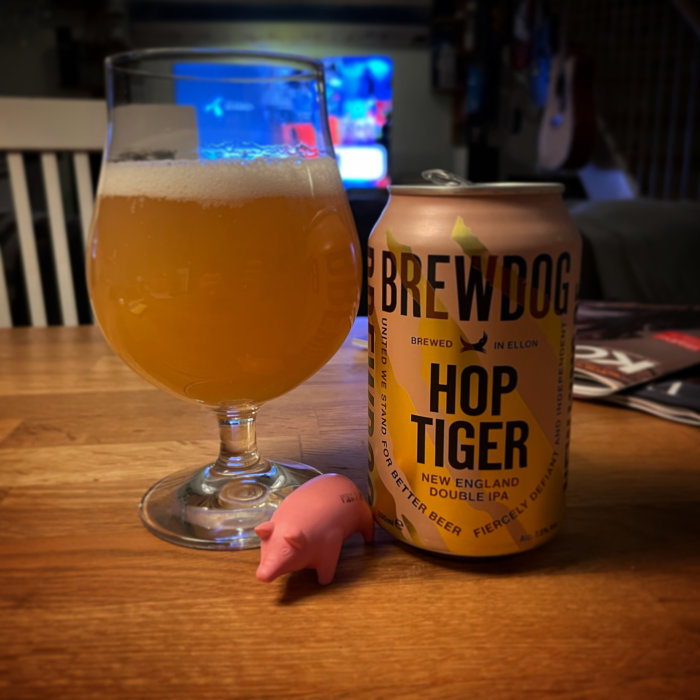 Ölglas med öl, Brewdog burk, stressleksak gris, oskarp bakgrund med skärmtittande.