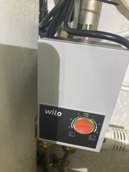 Bild av Wilo-cirkulationspump för värmesystem med hastighetsinställningar och kablage, monterad på rör.