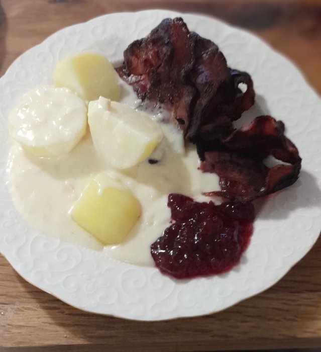 Ett fat med mat: potatis, gräddsås, stekt bacon och lingonsylt. En traditionell svensk måltid.