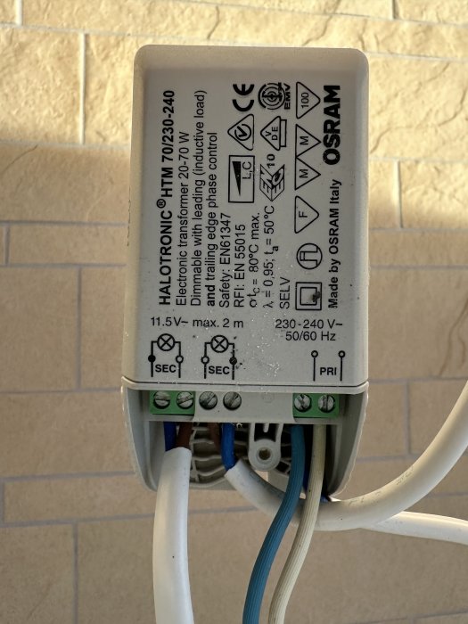 Elektronisk transformator för belysning, väggmontering, ledningar anslutna, tekniska specifikationer, märkt med varningsikoner och tillverkarlogotyp.