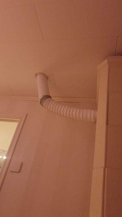 Flexibel ventilationsslang som går längs rosa vägg och tak i rum.