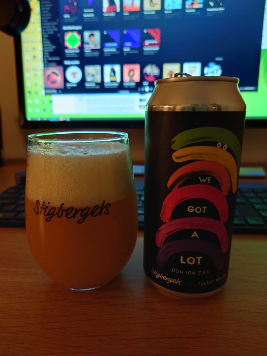 Ett ölglas märkt "Stigbergets" med skum, och en ölburk framför en datorskärm.