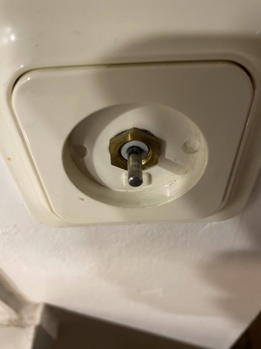 En närbild av en demonterad pappershandduksdispenser utan rulle, visande spolen och monteringsdetaljer.
