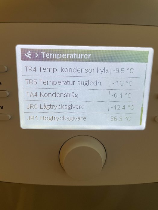 Digital kontrollpanel visar temperaturer för kylsystemkomponenter på svenska, med en justeringsknapp nedanför.