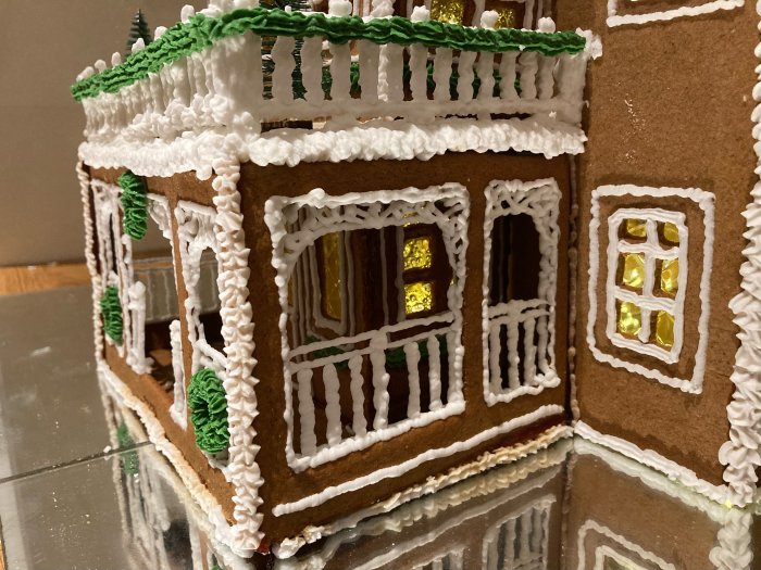 Ett detaljerat pepparkakshus med kristyr och strössel som liknar snö och belysning.