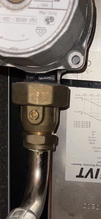 Metallvärmemätare och mässingsventil mot datablad i suddig bakgrund. teknisk installation.