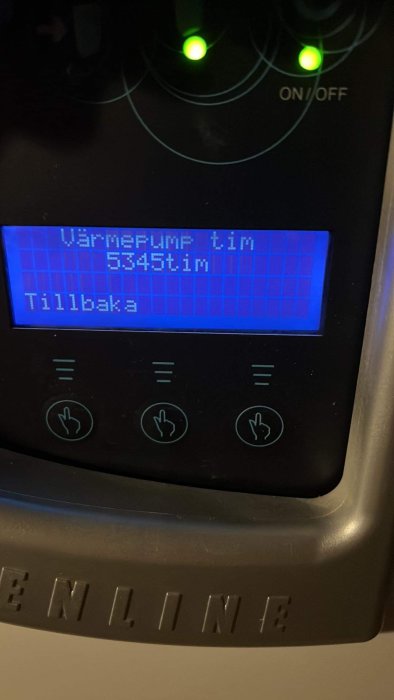 LCD-display visar "Värmepump tim 5345tim". Gröna indikatorlampor och knappar under. Apparatpanel, möjligen för värmesystem.