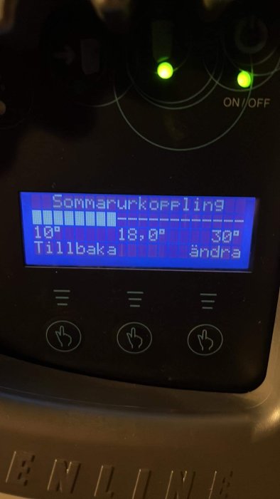 Digital display visar "Sommartidkoppling", tid och temperatur, på en apparat med knappar och lysande indikatorer.