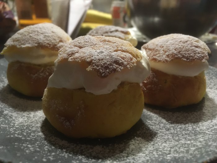 Tre semlor med grädde och mandelmassa, pudrade med florsocker på ett fat.